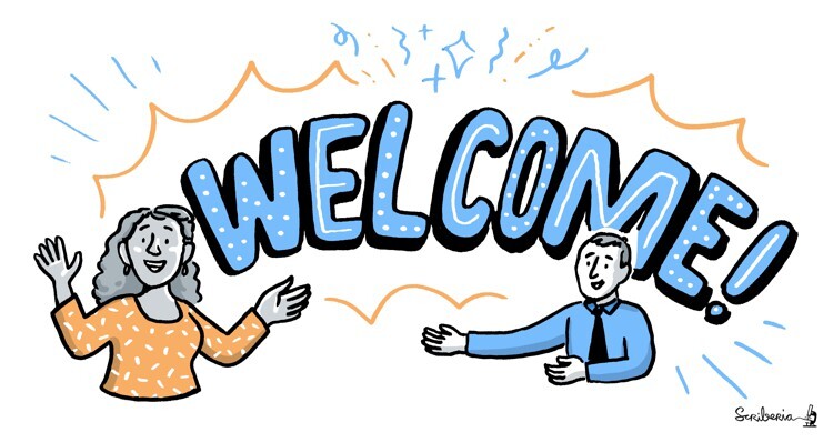 Alt: Two people, one woman with a long orange shirt and one guy with a blue shirt and a tie, and a large Welcome! sign at the back